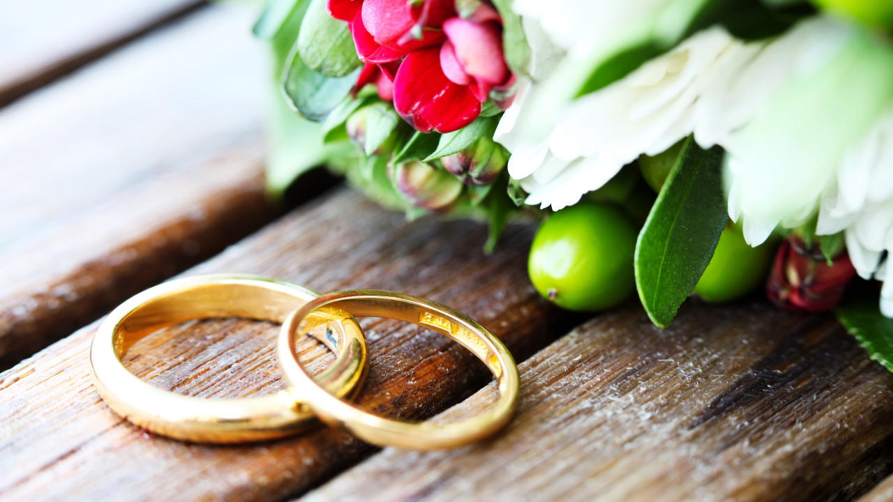 Two gold wedding rings with a bouquet of flowers