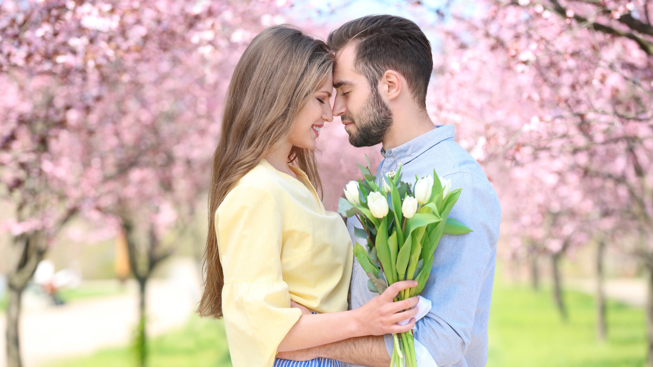 Влюбленная пара стоит в цветущем парке