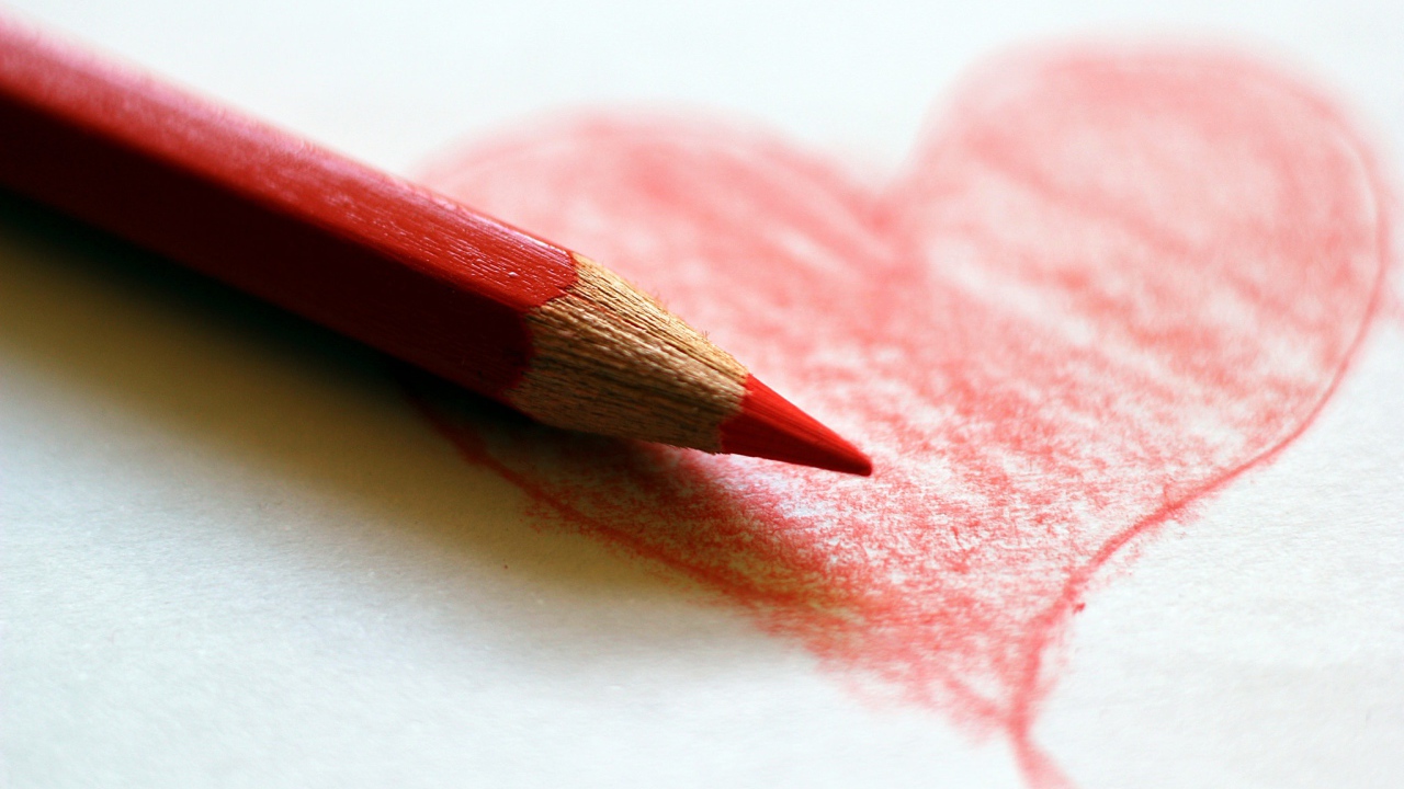 Нарисованное карандашом красное сердце на бумаге