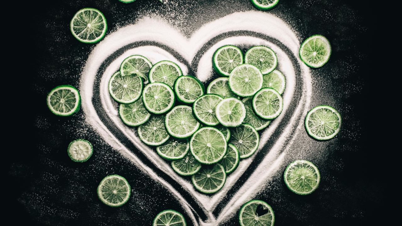 Сердце из сахара и кружочков  зеленого лайма на черном фоне