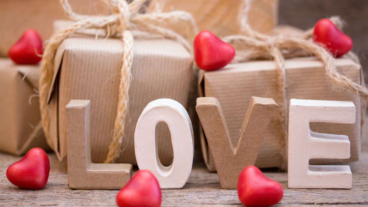 Романтические подарки и надпись Love с красными сердечками