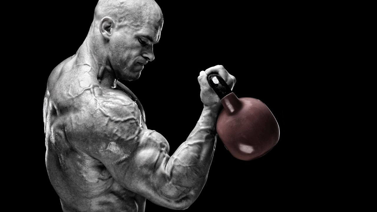 Сильный накаченный мужчина бодибилдер с гантелей в руках