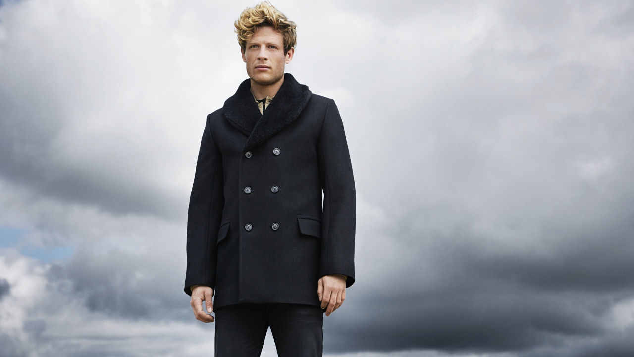 Актер Джеймс Нортон в черном пальто на фоне неба