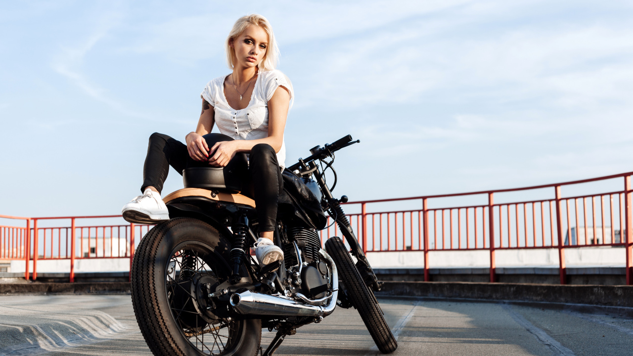 Beautiful blonde is sitting on a black motorcycle