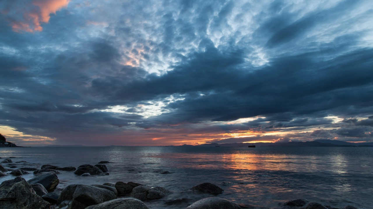 Валуны в воде на берегу на фоне пасмурного неба 