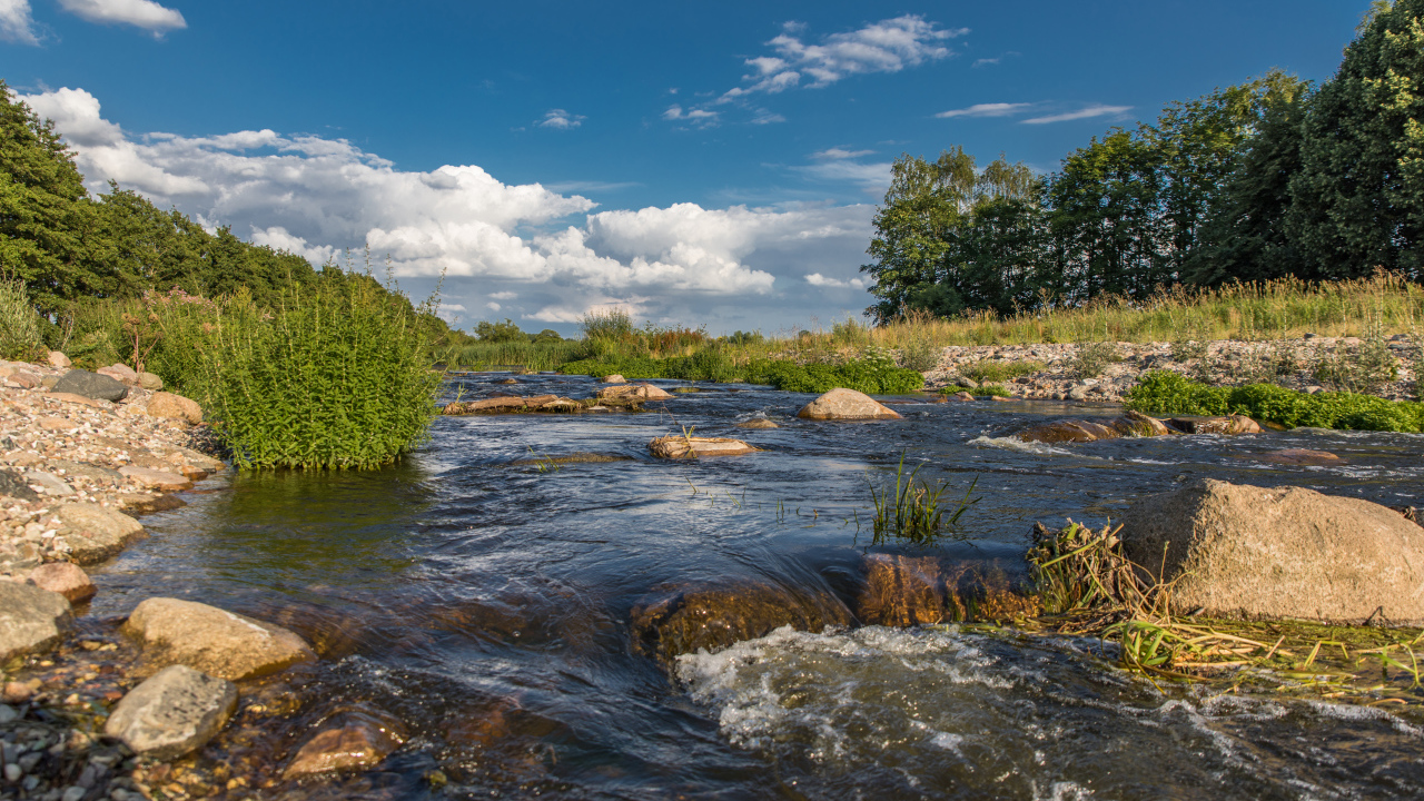 Быстрая речная вода стекает по камням под красивым голубым небом