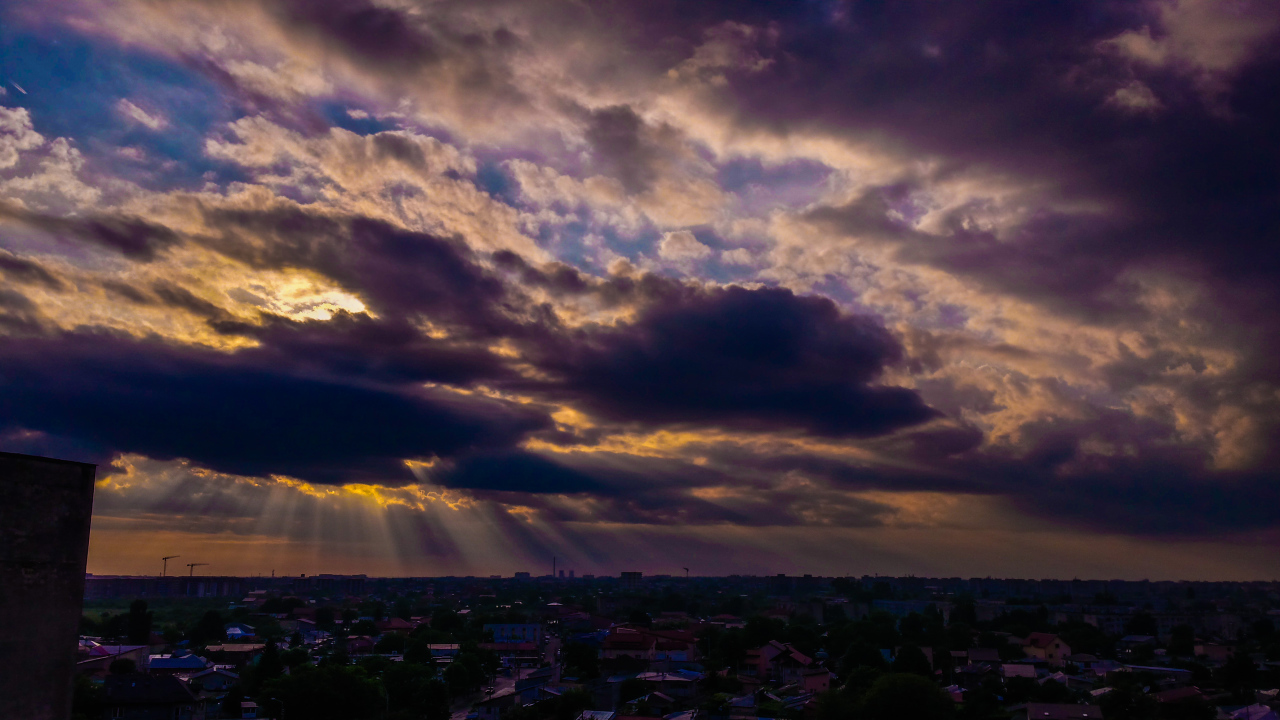 Лучи солнца пробиваются сквозь облака над городом