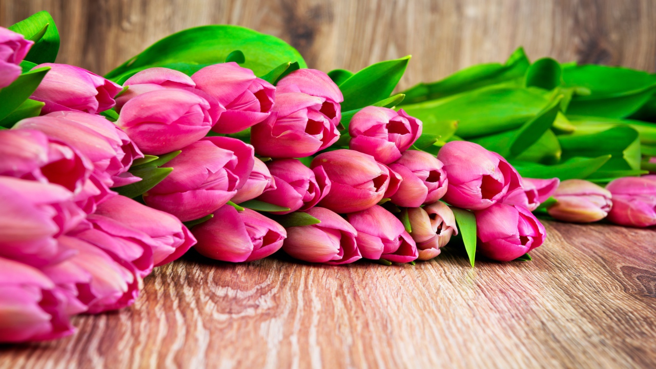 Букет розовых тюльпанов лежит на деревянной поверхности