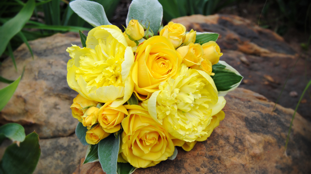 Букет желтых роз с желтыми пионами лежит на камне