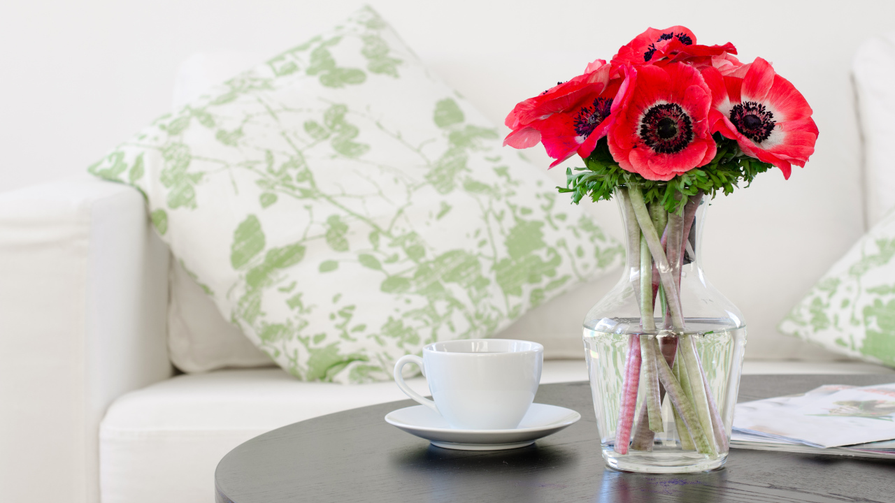 Букет красных цветов анемоны в вазе на столе с белой чашкой