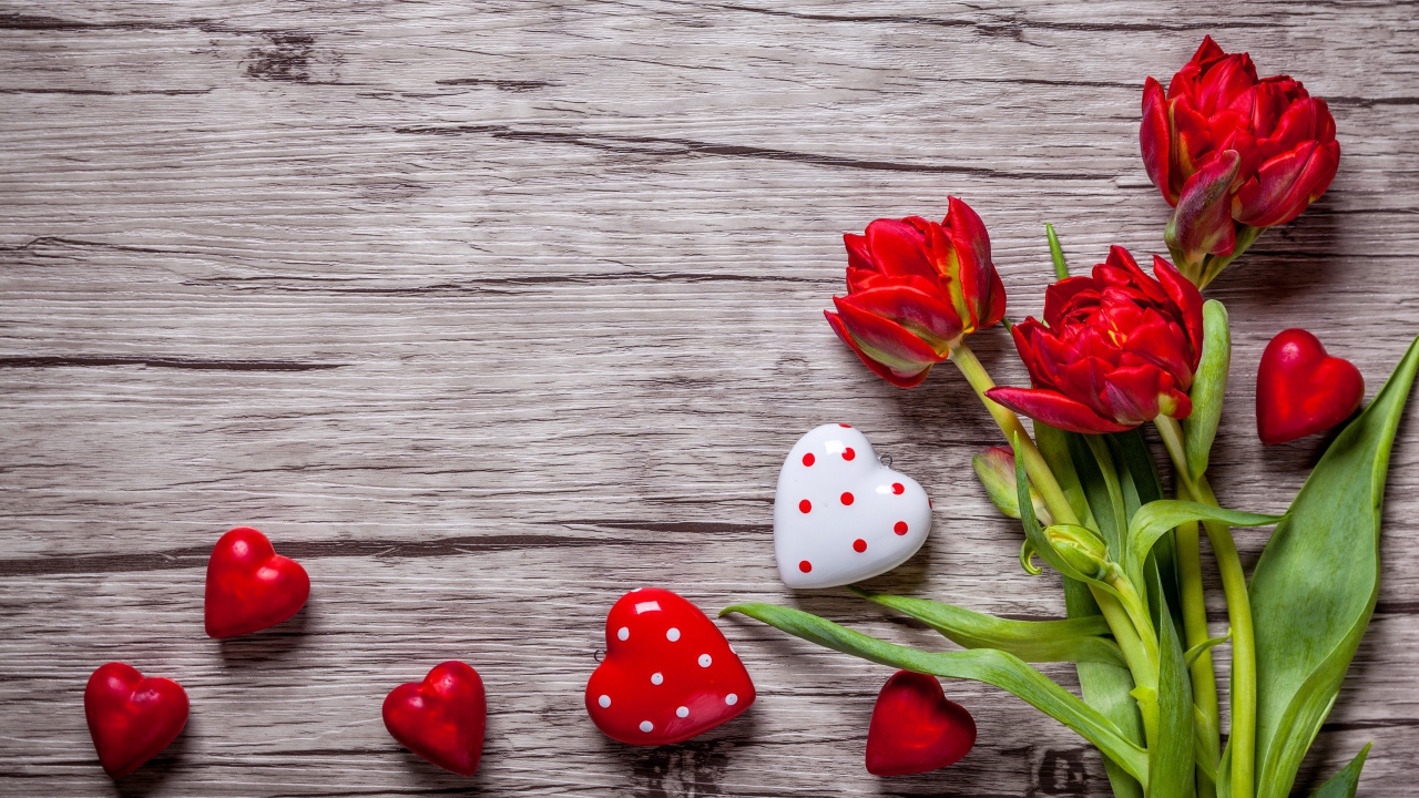 Красные красивые тюльпаны с сердечками на деревянной поверхности