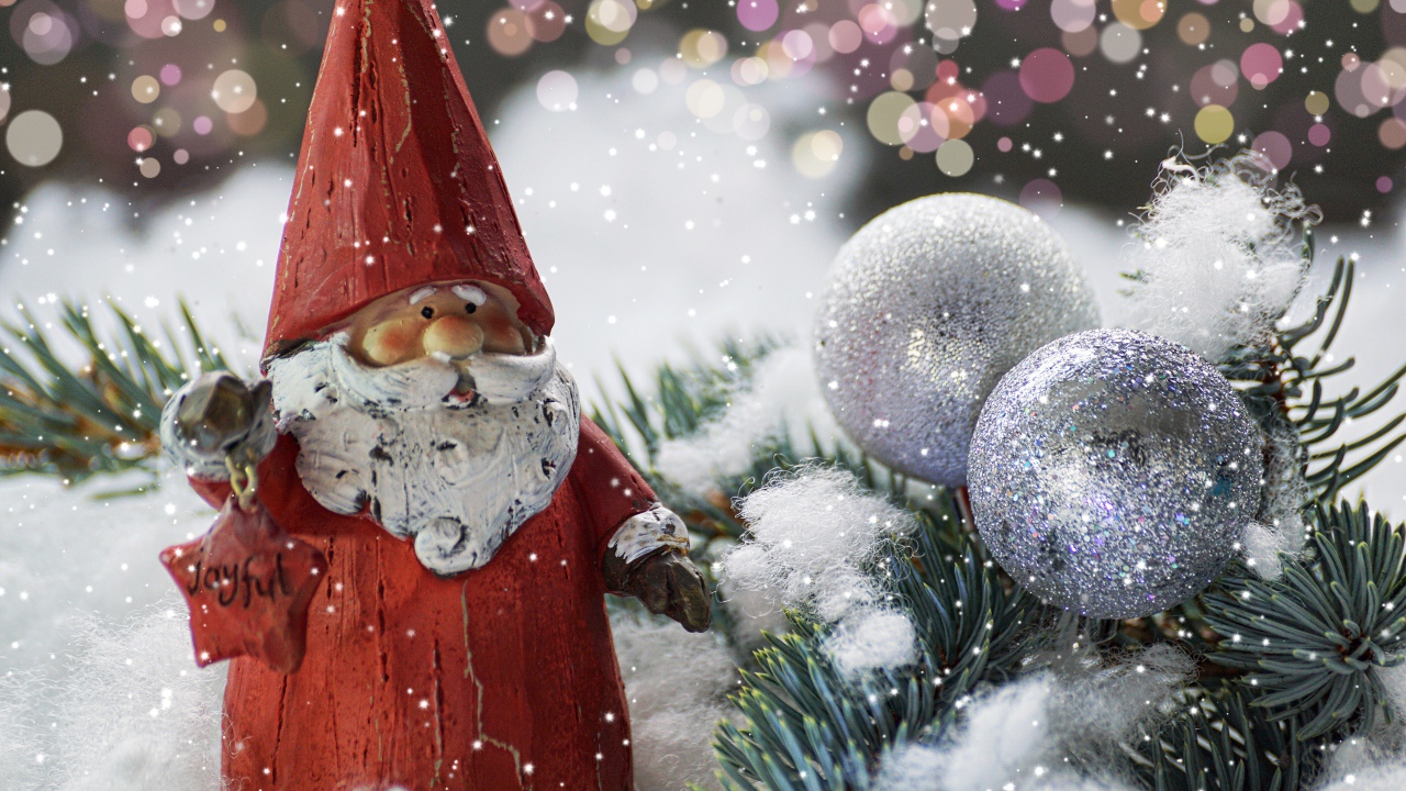 Статуэтка деда Мороза рядом с еловой веткой и яркими шарами