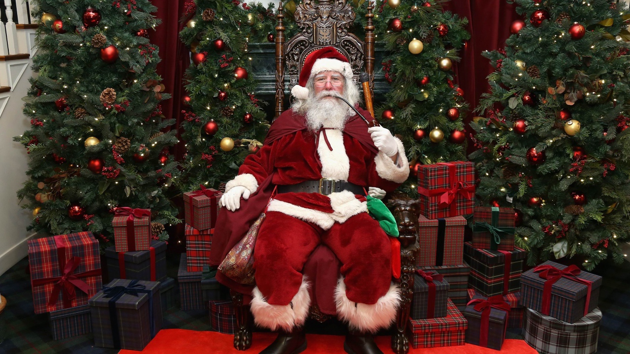 Санта Клаус курит трубку сидя в кресле