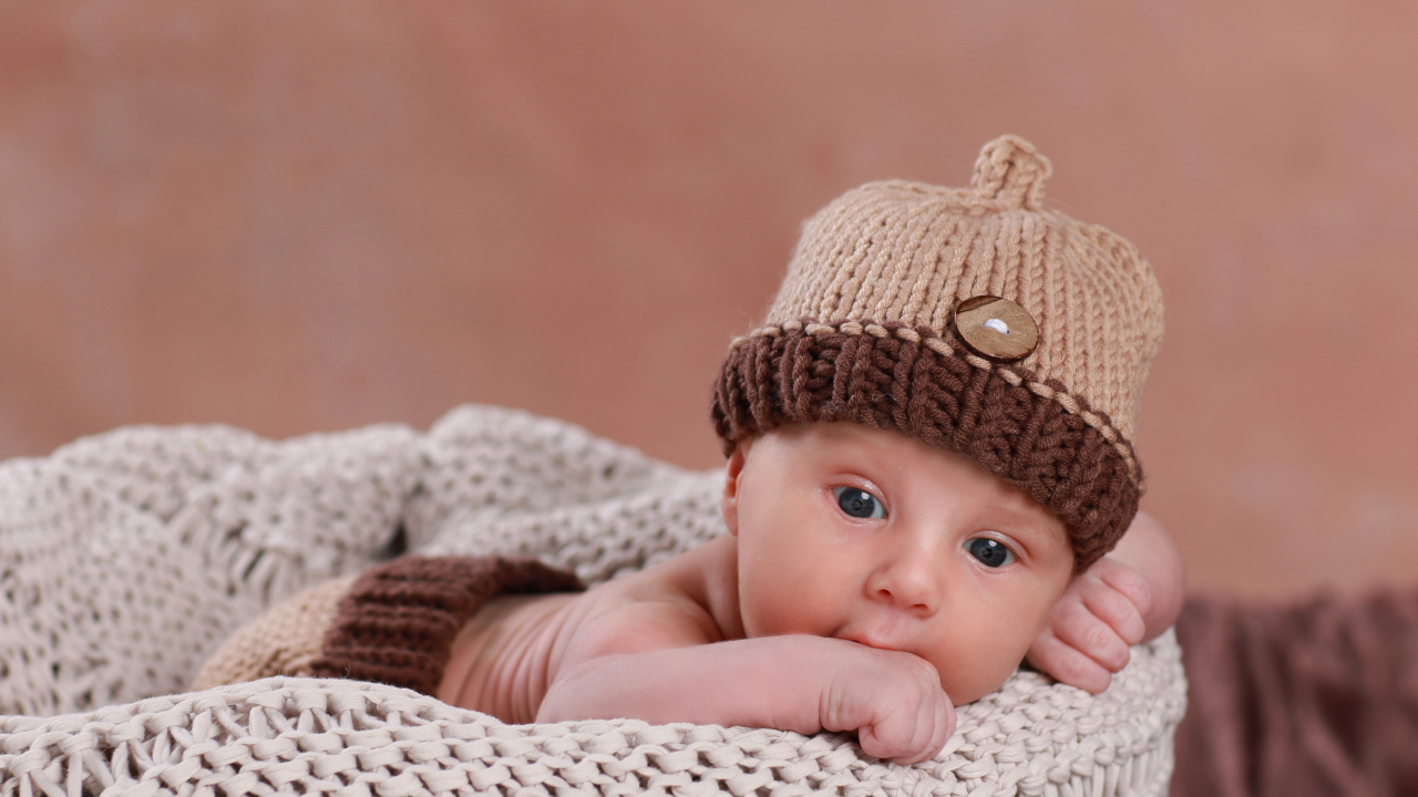 Грудной ребенок в вязаной коричневой шапке