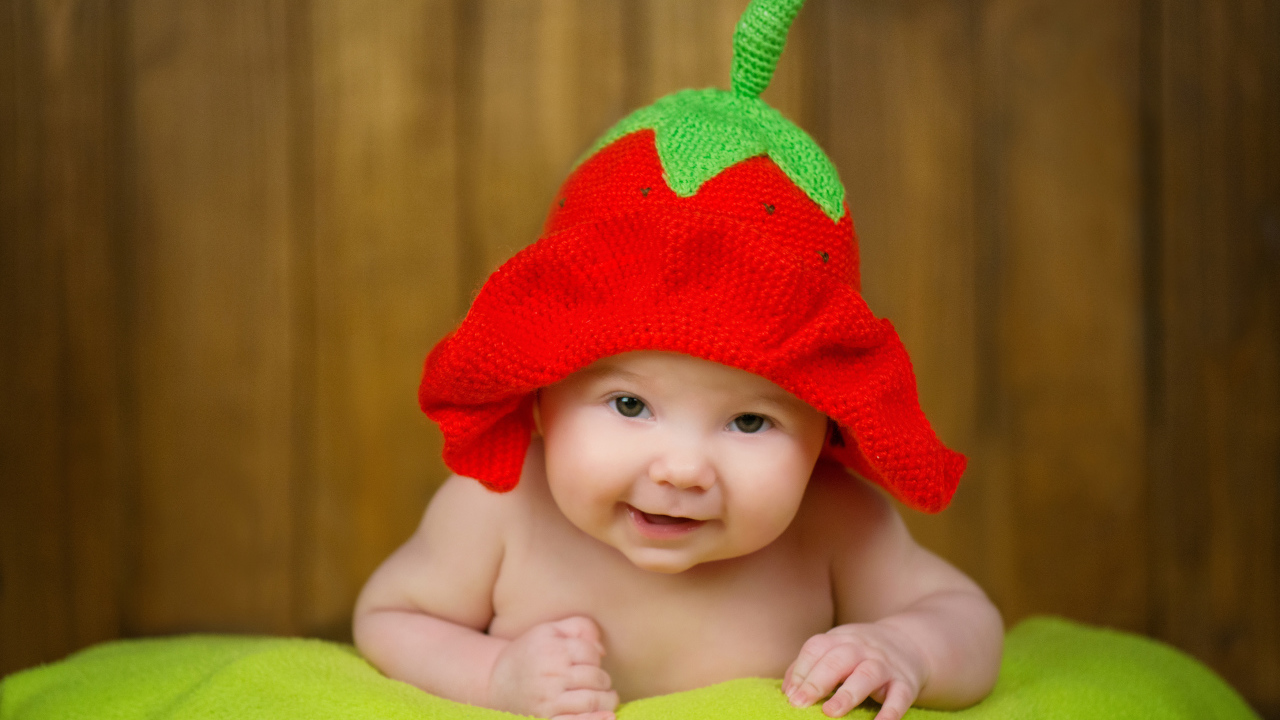 Младенец в забавной шапке клубнике на голове