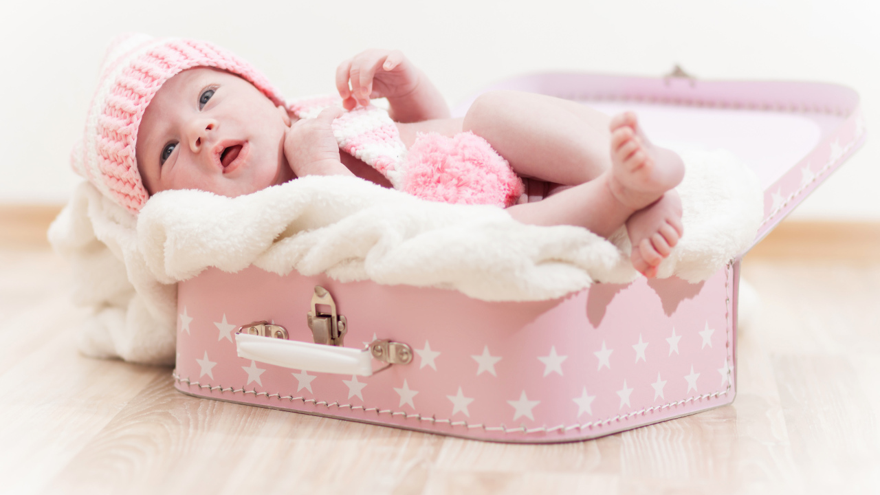 Милый младенец лежит в розовом чемодане