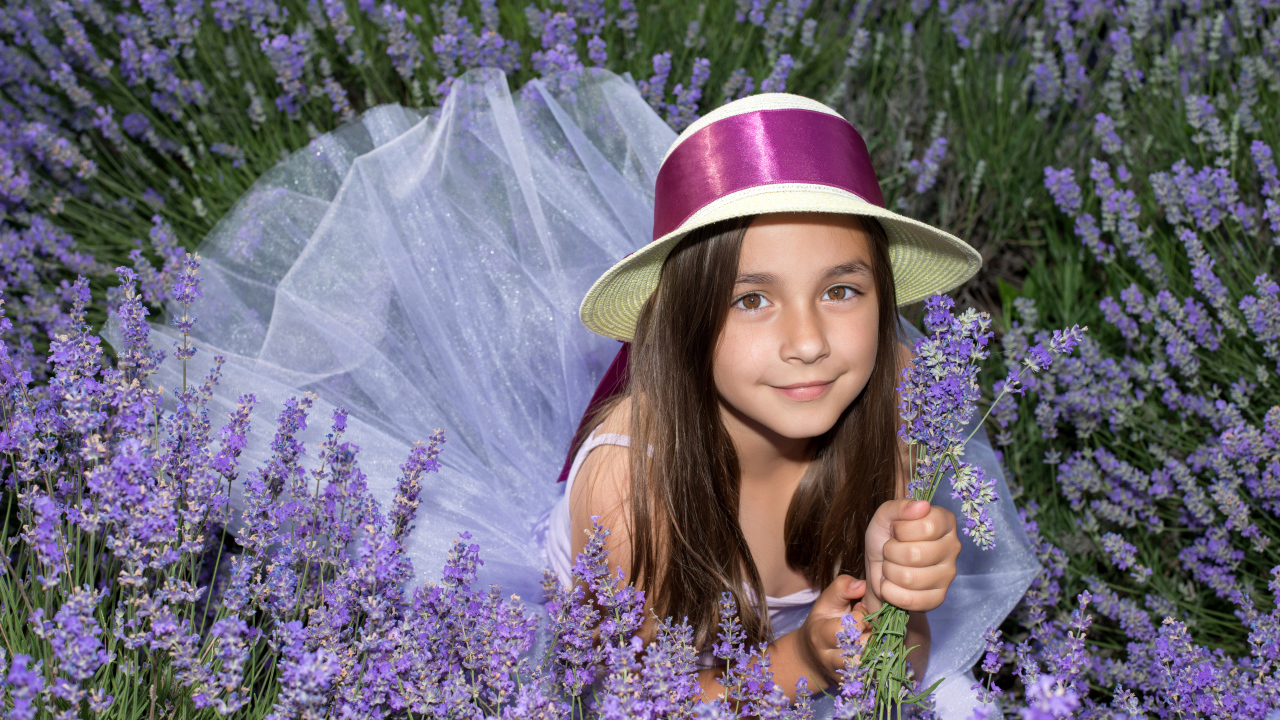Девочка в шляпе лежит в фиолетовых цветах лаванды