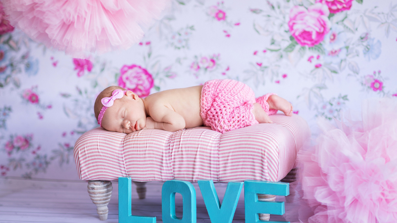 Спящий грудной ребенок в розовом костюме и надписью love