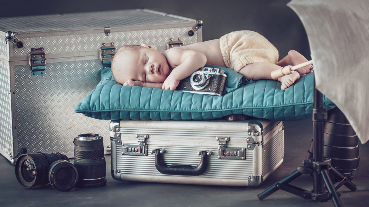 Спящий младенец с фотоаппаратом спит на чемодане