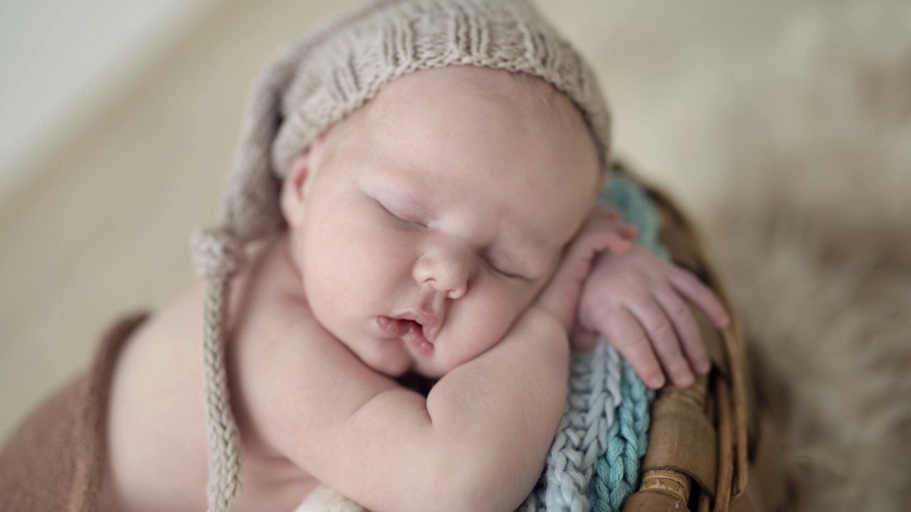 Маленький грудной ребенок спит в вязаной шапке