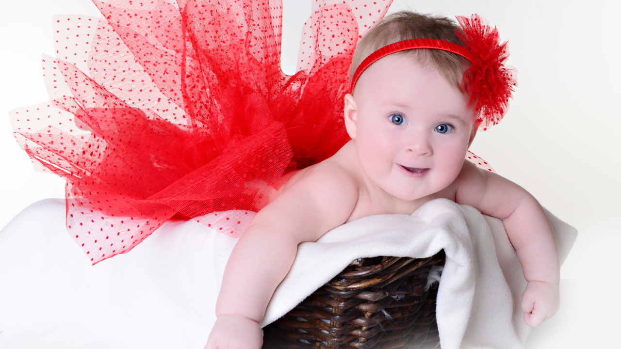 Маленькая голубоглазая девочка в красном красивом платье лежит в корзине