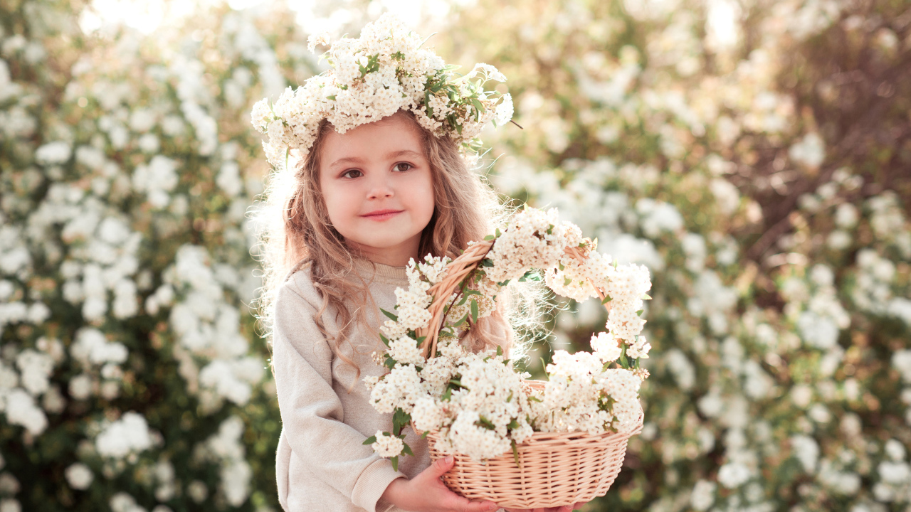 Милая маленькая девочка с венком на голове и корзиной белых цветов