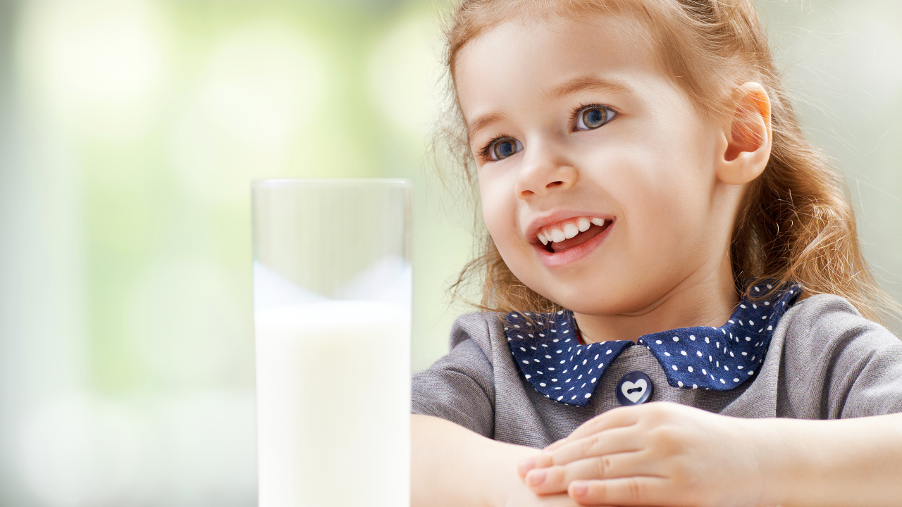 Красивая кареглазая девочка со стаканом молока