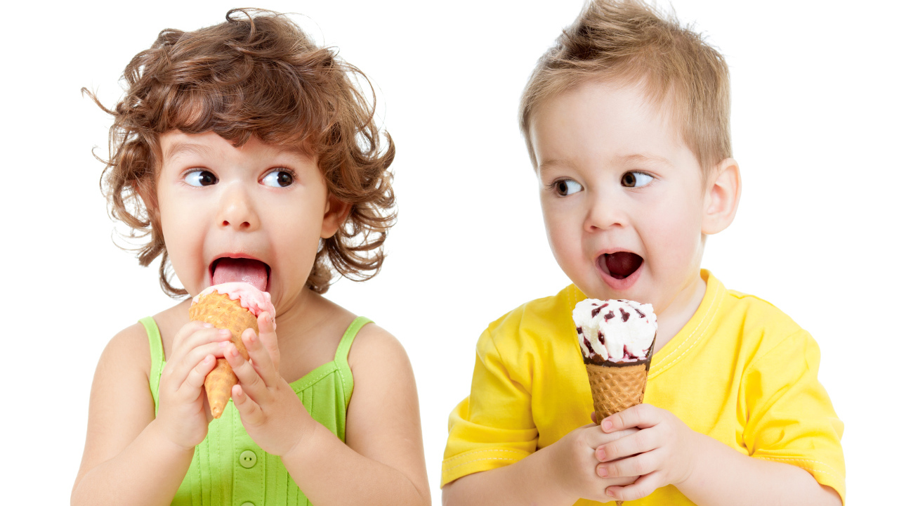 Маленькие мальчик и девочка едят вкусное мороженое