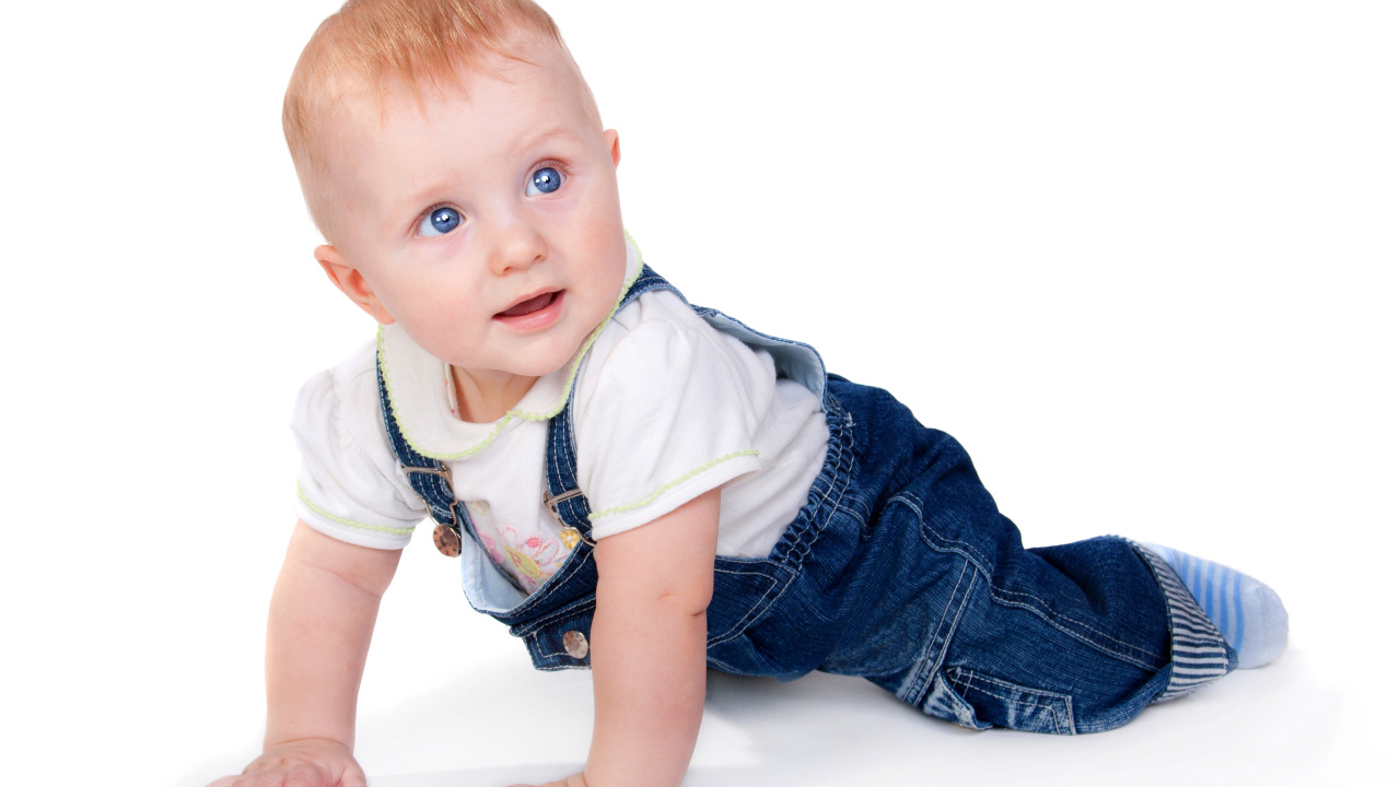 Маленький мальчик в синем комбинезоне на белом фоне