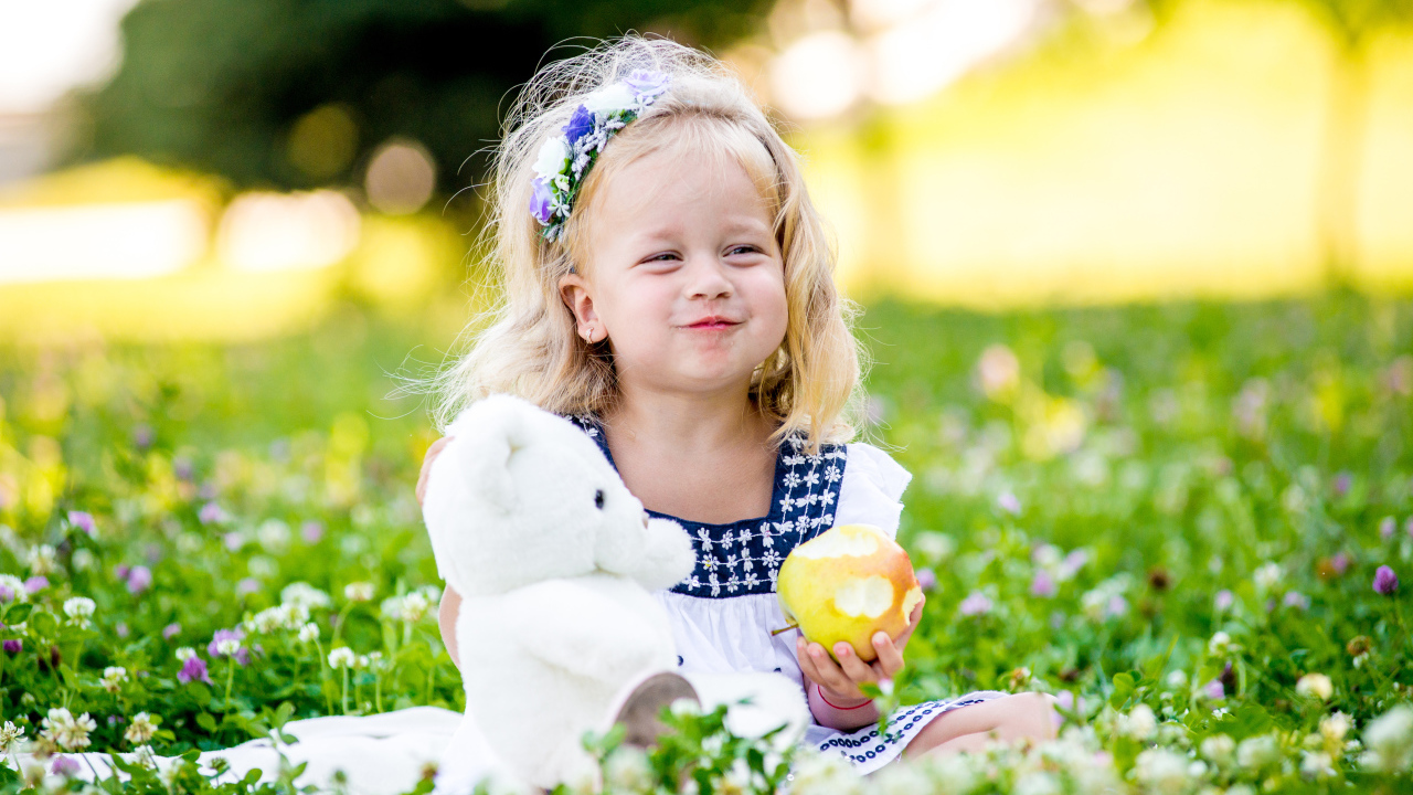 Маленькая девочка с белым медвежонком в руках и большим яблоком