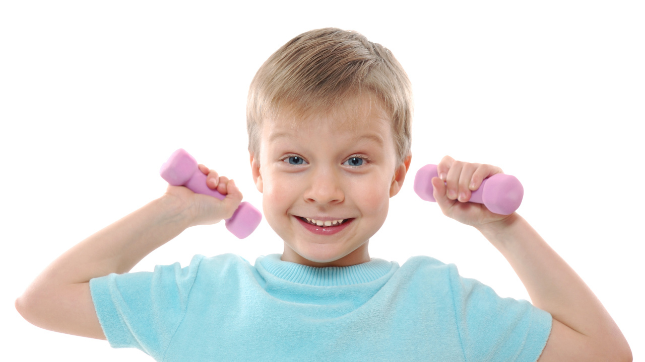 Маленький улыбающийся мальчик с гантелями на белом фоне
