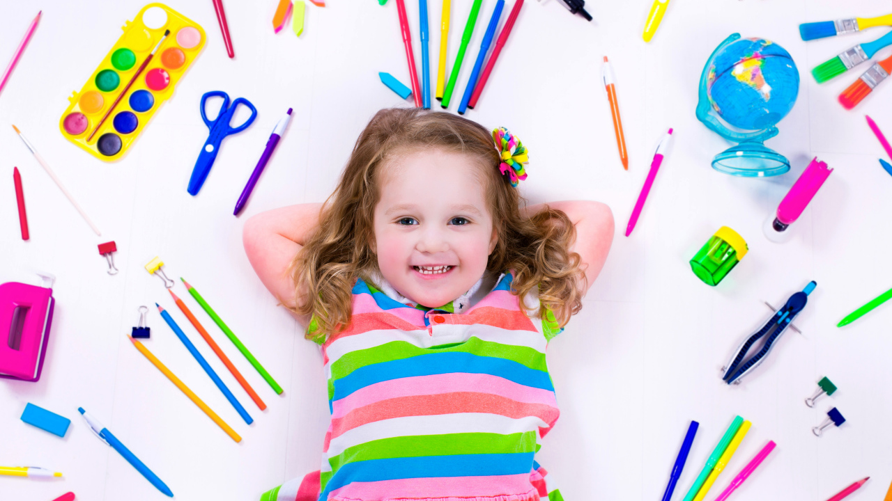 Маленькая улыбающаяся девочка со школьными принадлежностями