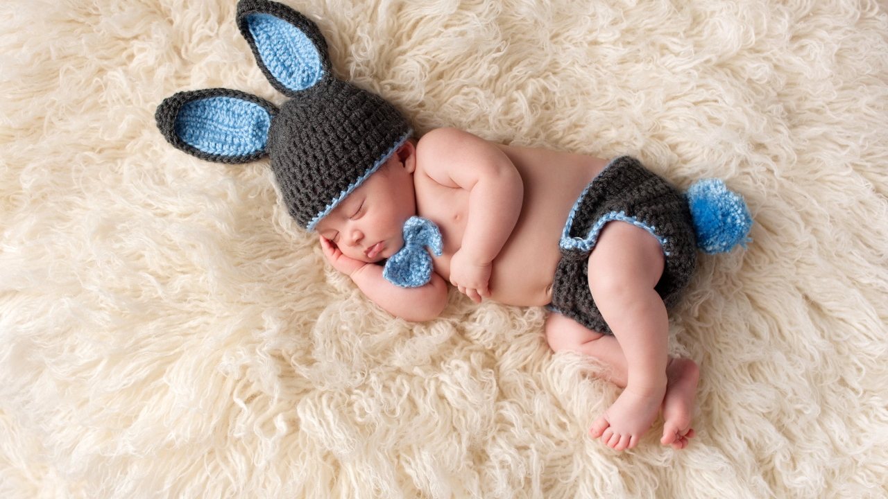 Спящий младенец в вязаном костюме зайца