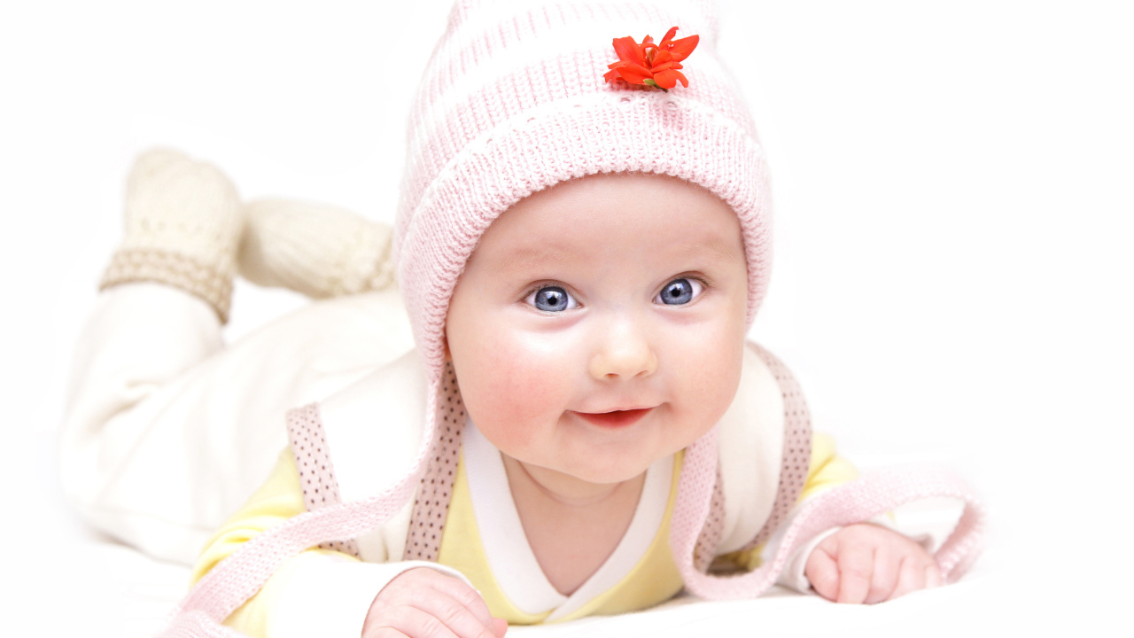 Улыбающийся голубоглазый малыш в розовой шапке