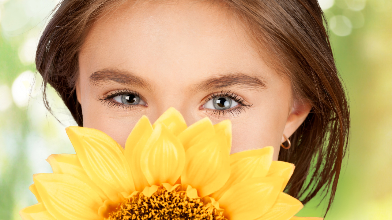 Взгляд маленькой девочки шатенки с подсолнухом в руках