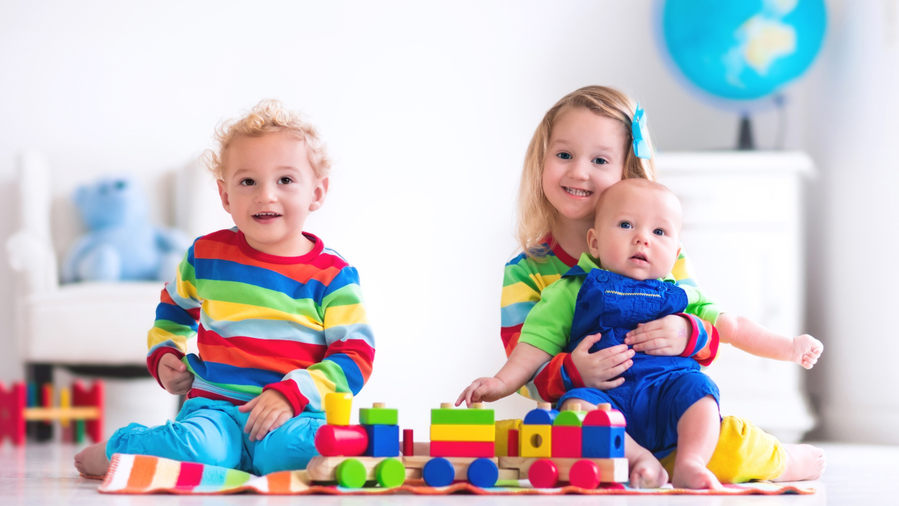 Три ребенка играют с игрушечным поездом