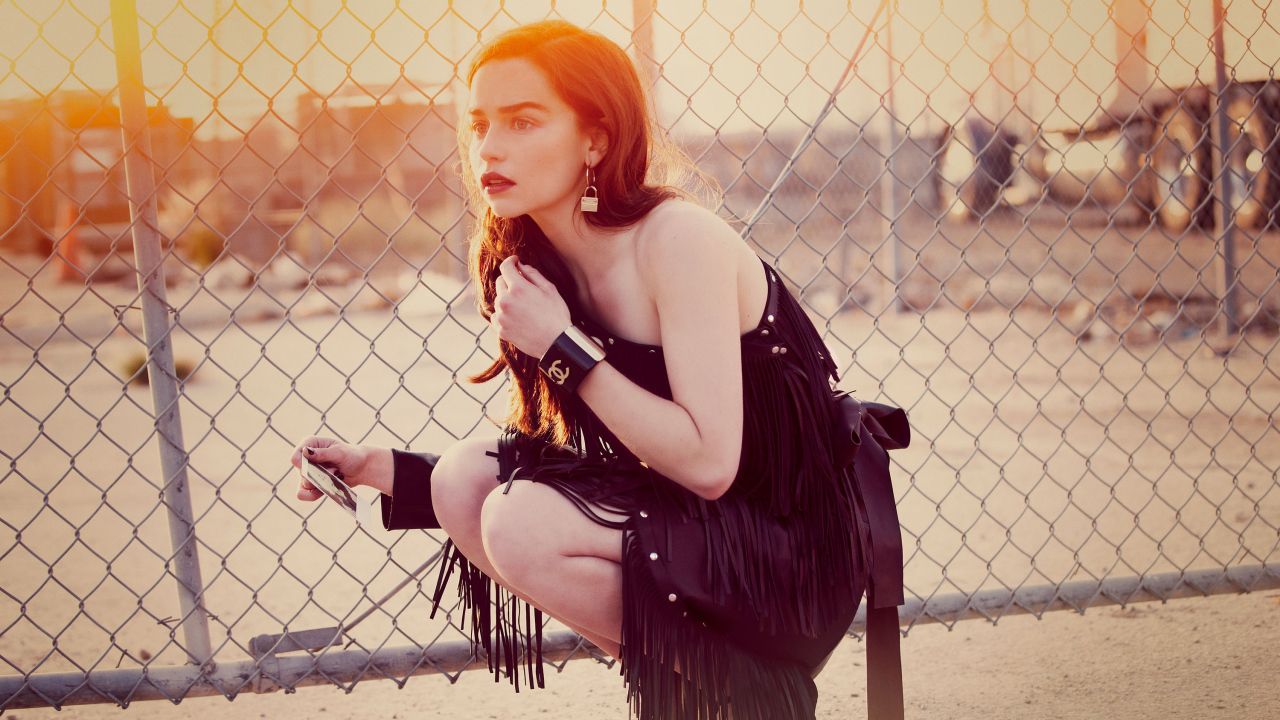 Актриса Эмилия Кларк в красивом черном платье в лучах солнца