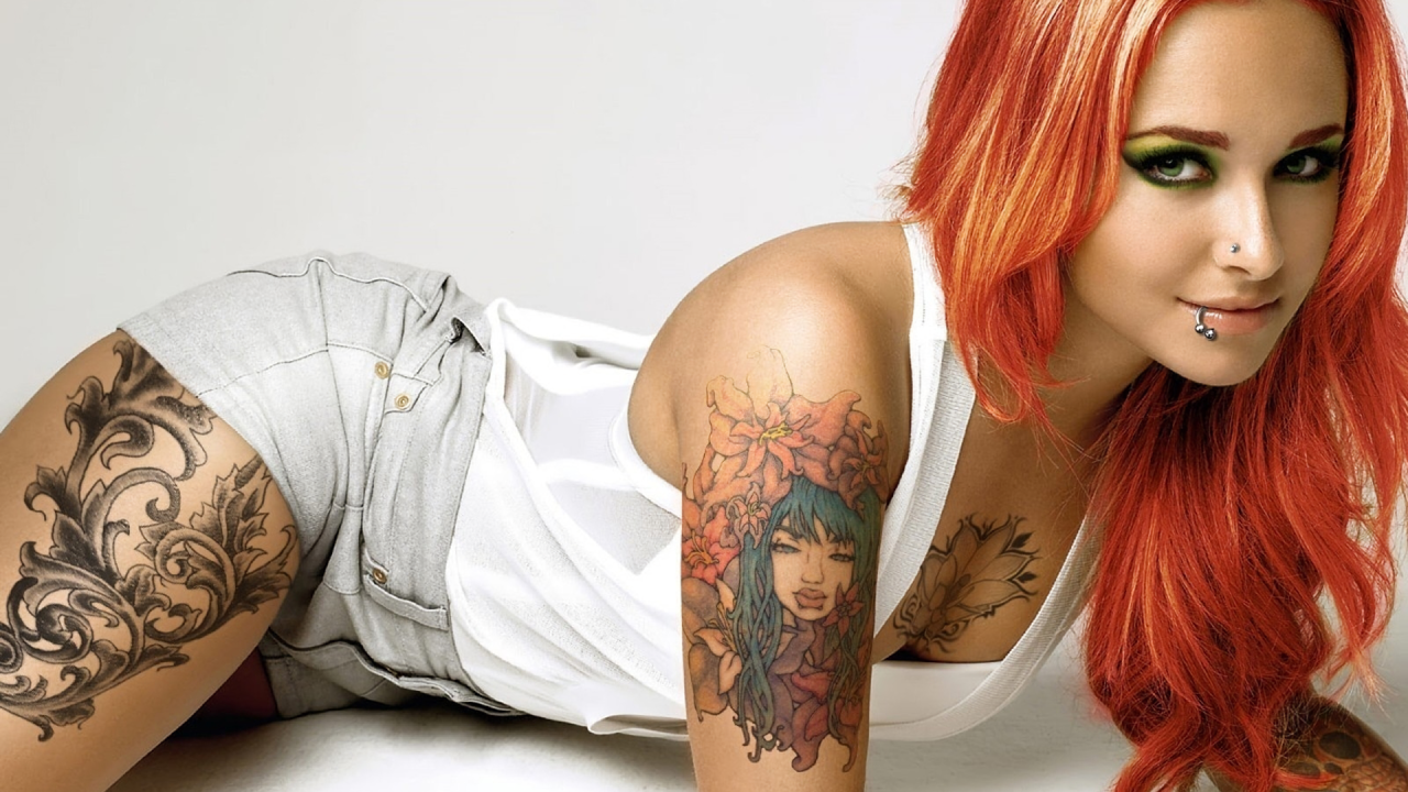 Красивая рыжеволосая девушка с пирсингом и татуировками