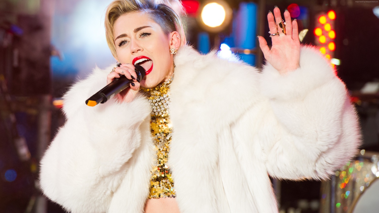 Popular young singer Miley Cyrus in a white fur coat on stage
