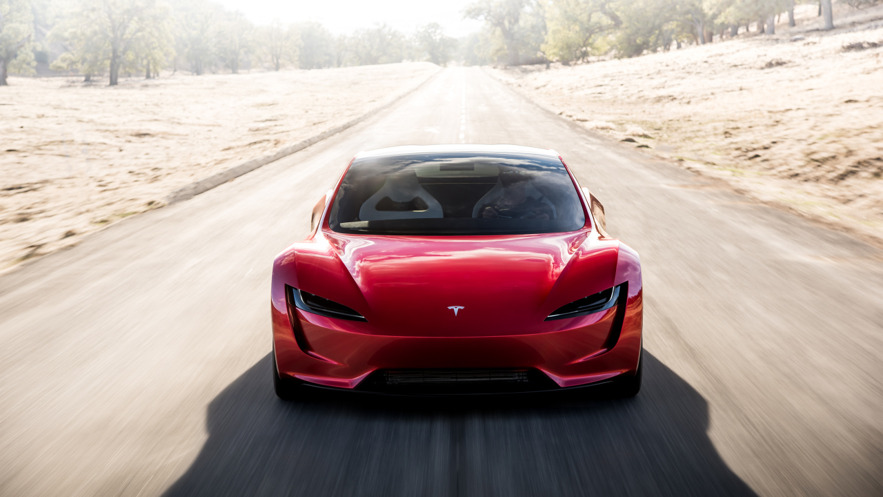 Красный автомобиль Tesla Roadster на трассе, вид спереди