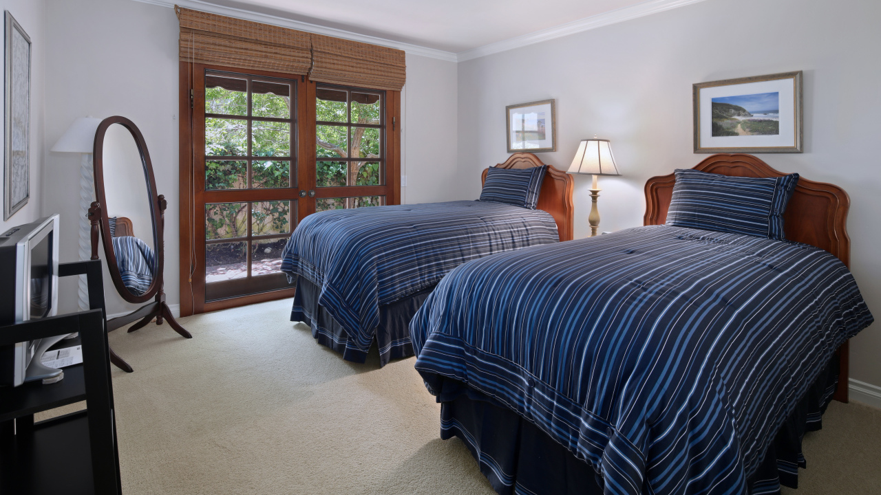 Две большие кровати в спальне с деревянным окном
