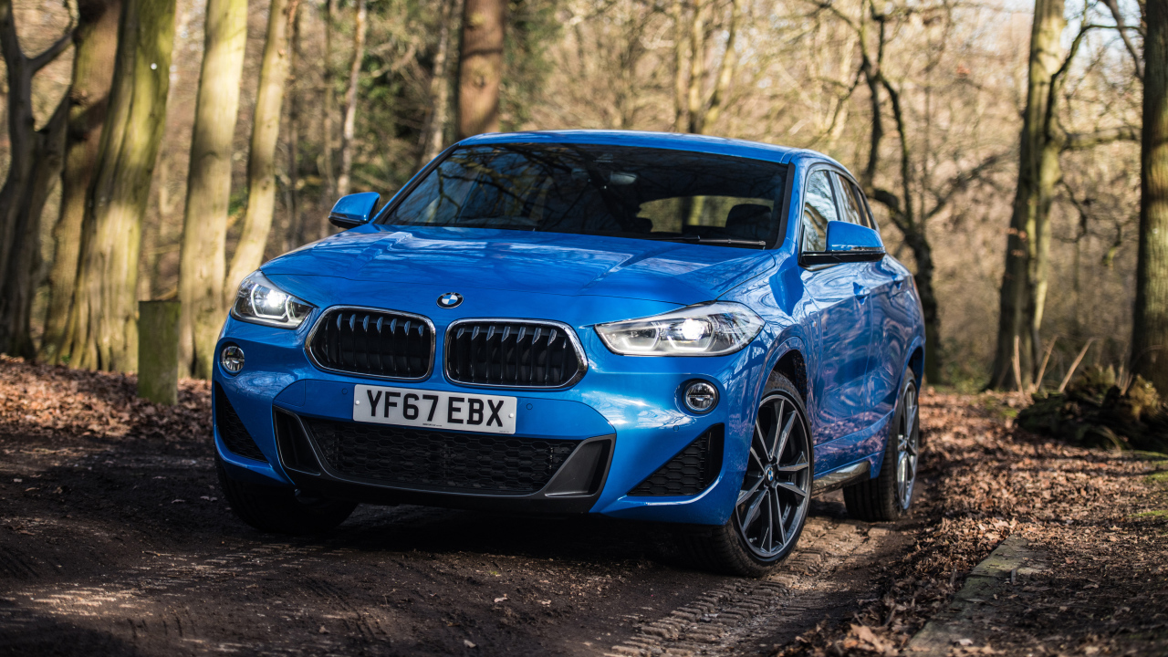 Синий автомобиль BMW X2 xDrive20d M Sport, 2018 на дороге в лесу
