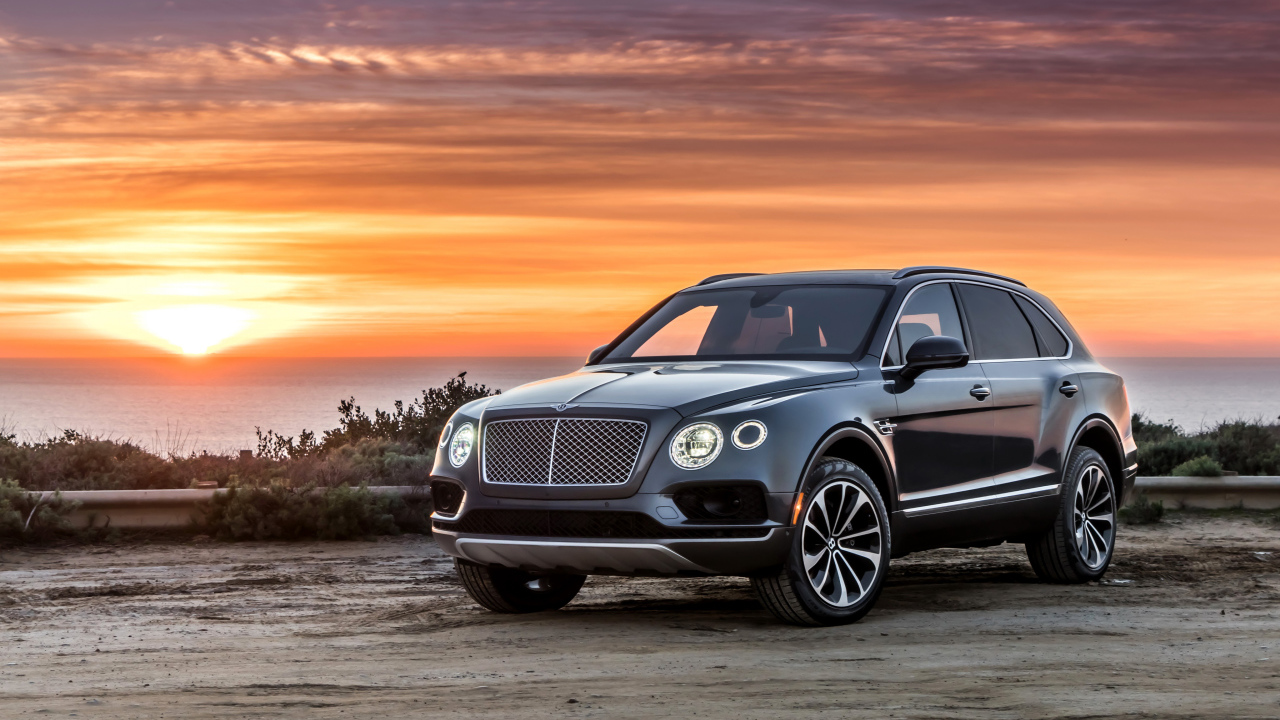 Черный стильный стильный автомобиль Bentley на фоне заката 