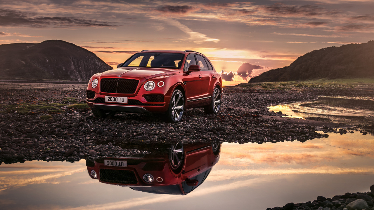 Красный автомобиль Bentley Bentayga V8, 2018 года на фоне заката 