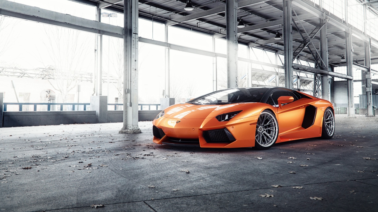 Оранжевый автомобиль Lamborghini Aventador под мостом