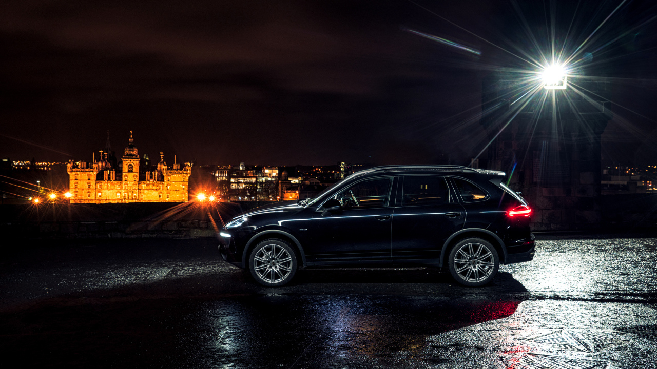 Черный автомобиль Porsche Cayenne в свете фонаря 