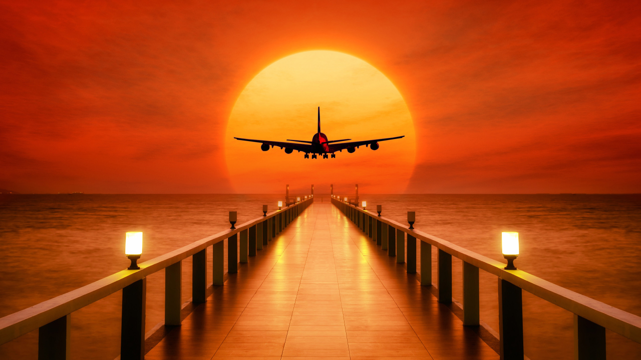 Самолет идет на посадку на закате солнца над океаном