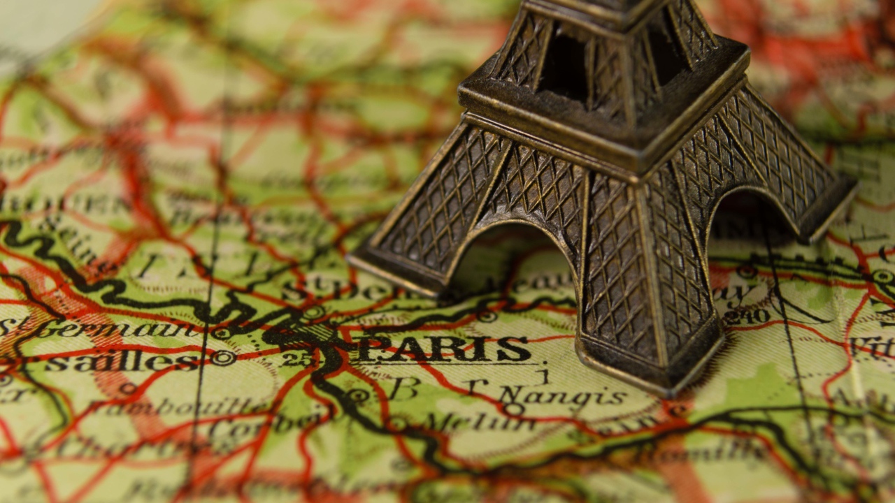 Маленькая статуэтка Эйфелева башня стоит на карте