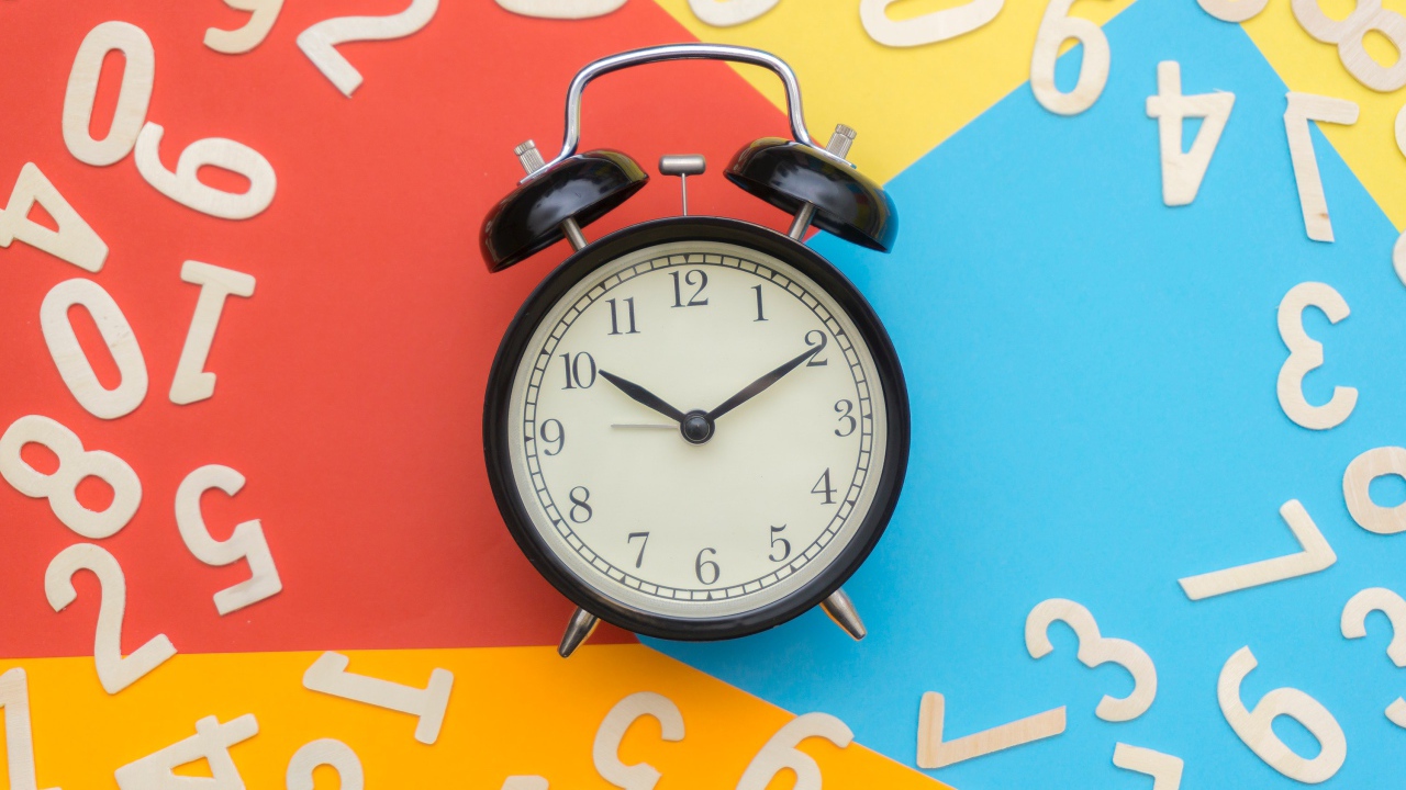 Alarm clock on a multicolored background with numbers