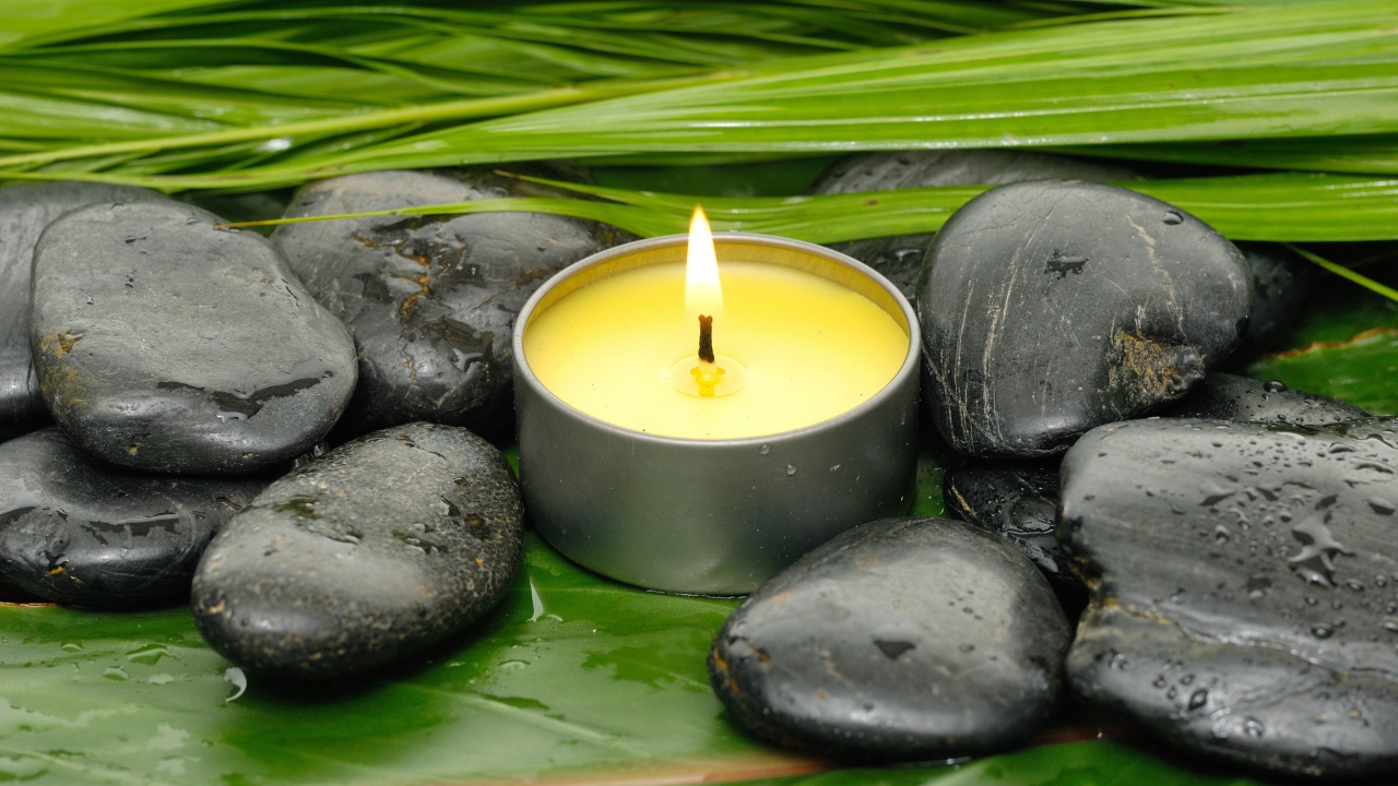 Зажженная свеча и черные камни для SPA